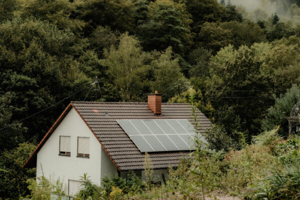 Small home with a solar panel on the roof nestled in the hills with fog just over the hill.